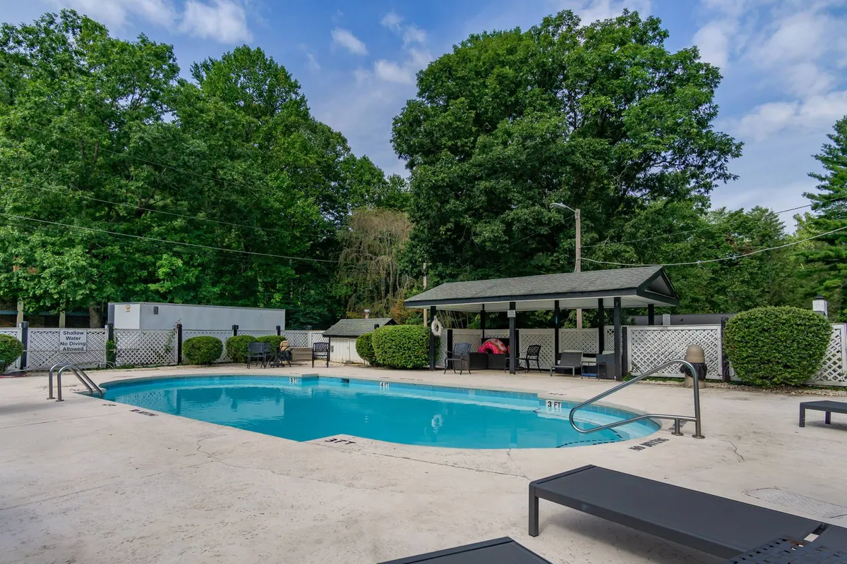 A sparkling outdoor swimming pool surrounded by lounge chairs and lush greenery, with a cabana nearby for shade. The inviting pool area is perfect for swimming, sunbathing, socializing, and unwinding after a day of adventure.